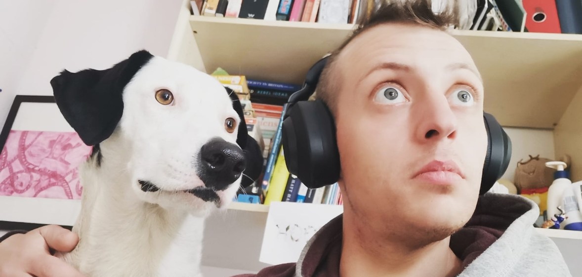 Matty Sheldrick wears headphones and poses with their dog Lola