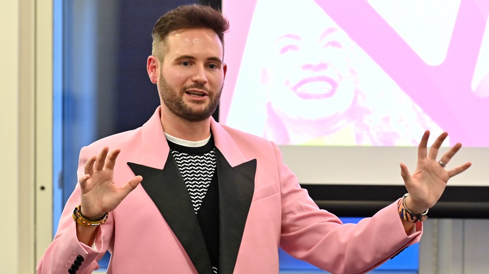 PinkNews' Chief Operating Officer Anthony James wears a pink blazer with black lapels as he speaks at the PPA Independent Publisher Conference and Awards on 25 November 2022 (PPA)