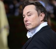 Elon Musk turns his head, eyebrow raised, giving a stern look to the camera.