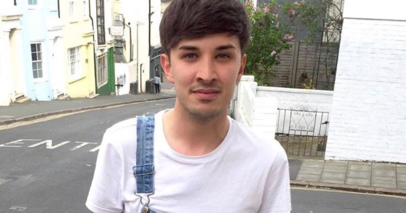 A photo of one of the Manchester Arena bombing victims, Martyn Hett, wearing a white t-shirt and dungerees with one strap, smiling outside a street corner.