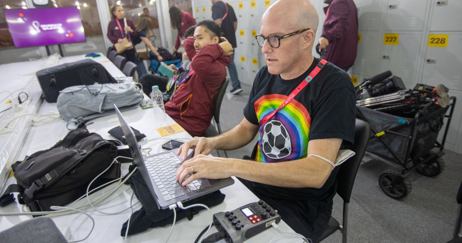 Sports journalist Grant Wahl typing on a laptop in the spacious media center of the Qatar World Cup.