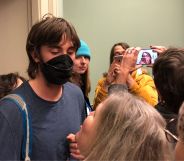 A person stands staring at an individual looking up at them while crowded around people