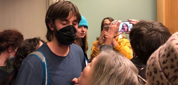 A person stands staring at an individual looking up at them while crowded around people