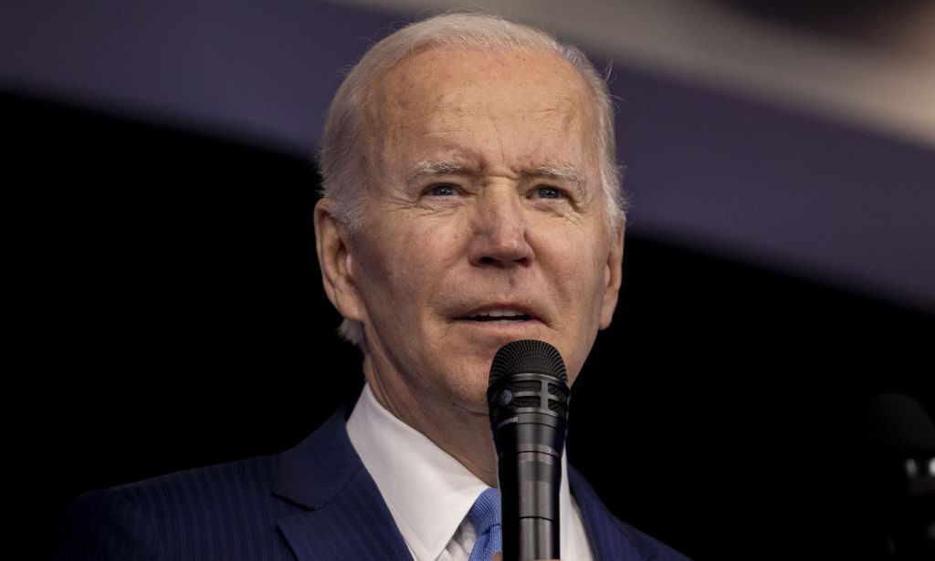 Biden stands speaking to a crowd through a microphone.