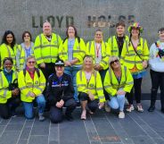 Members of the Birmingham StreetWatch crew wear yellow high-vis jackets, smiling in front of the police headquarters.