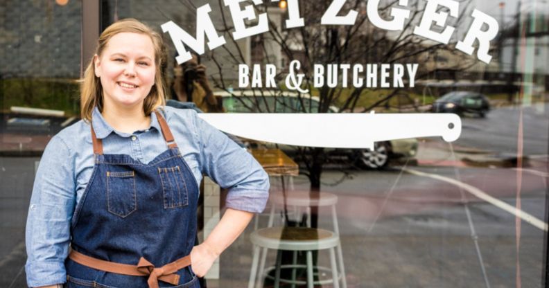 Metzger Bar and Butchery owner Brittanny Anderson stands outside her restaurant, wearing denim dungarees and a blue top.
