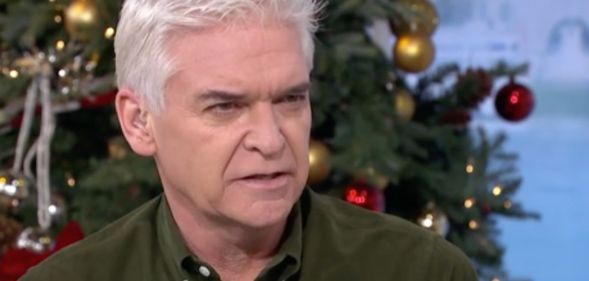 Phillip Schofield, who is wearing a green-brown shirt, talks to other people gathered for an episode of This Morning