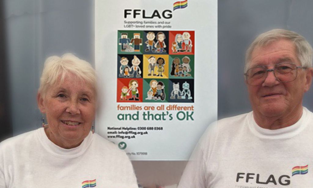 Sue and Bob Allen smile at the camera while wearing FFLAG shirts. FFLAG is a charity that helps families of LGBTQ+ youth