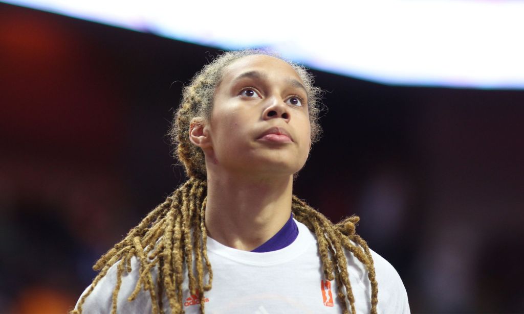 WNBA star Brittney Griner wears a white and purple top as she stares upwards during a basketball game