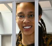 Brittney Griner smiles as she stands behind while bars while attending a Russian court hearing
