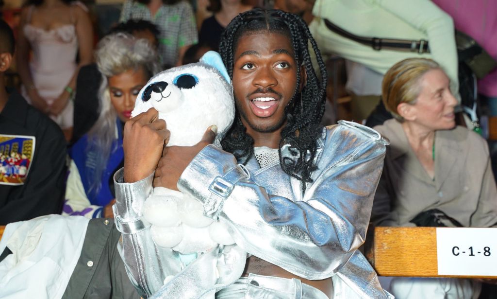 Lil Nas X holds a stuffed canine plush near his face while attending Vogue World