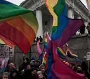 People hold up rainbow LGBTQ+ Pride flags and a sign reading 'stop hate' during a protest in Russia
