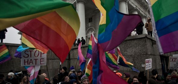 People hold up rainbow LGBTQ+ Pride flags and a sign reading 'stop hate' during a protest in Russia