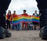 Activists stand side-by-side during a protest holding up rainbow LGBTQ+ flags in Russia