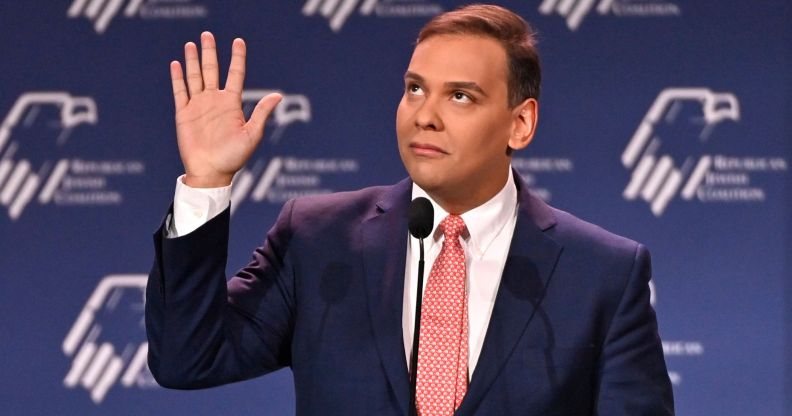 Republican politician George Santos gestures with his hands near his face while speaking at a podium