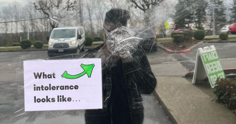 A photo showing the window of a bar in Seattle that had been shot. The glass is splintered and there is a sign stuck on the window just below the point of entry that says: "What intolerance looks like"
