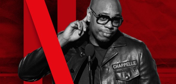 A graphic of comedian Dave Chappelle pointing to his ear as the red Netflix 'N' is wrapped around his arm.