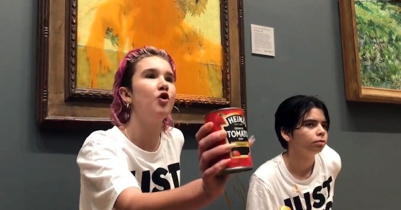 A photo of Just Stop Oil activists Anna Holland and Phoebe Plummer wearing T-shirts with the slogan "Just Stop Oil" kneel in front of Van Gogh's Sunflowers in London's National Gallery, which is covered in tomato soup