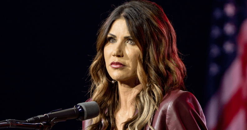 A photo shows South Dakota's republican governor Kristi Noem standing behind a microphone with the American flag can be seen in the background