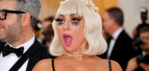 Lady Gaga wearing eyelash extensions, bright pink lipstick and revealing top attends the 2019 Met Gala
