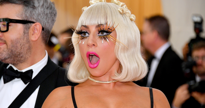 Lady Gaga wearing eyelash extensions, bright pink lipstick and revealing top attends the 2019 Met Gala