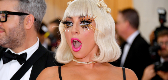 Lady Gaga wearing eyelash extensions, bright pink lipstick and revealing top attends the 2019 Met Gala