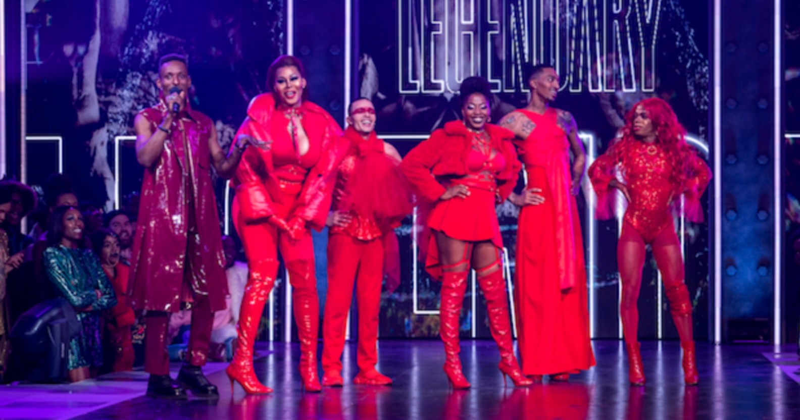 A screengrab from HBO's Legendary showing its contestants dressed in their red outfits on stage and also standing to the side dressed in his purple outfit is actor and dancer Dashaun Wesley who is the MC in the show.(HBO Max)