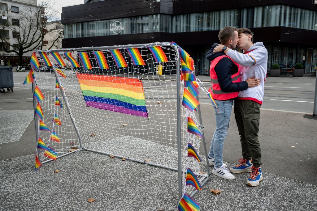 Two men kiss next to a goal during a symbolic action by LGBT+ associations in front of the FIFA museum in Zurich on November 8, 2022.