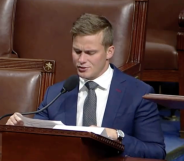 Dressed in a navy blue suit, white shirt and grey tie Madison Cawthorn gives his final address at the House of Representatives, sat a podium and talking into a microphone