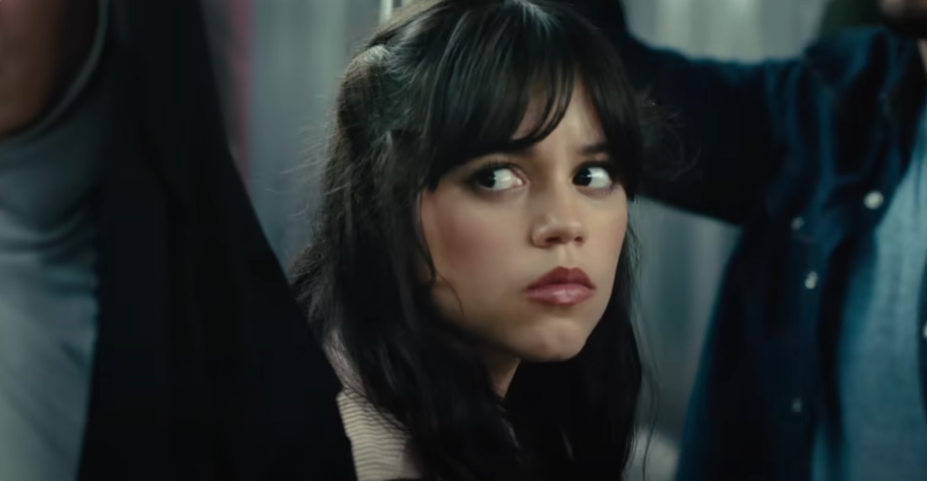 A still from upcoming movie Scream 6 shows actor Jenny Ortega with long dark hair sitting down in a subway train looking worried