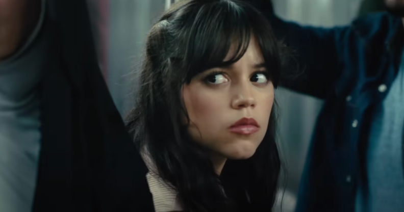 A still from upcoming movie Scream 6 shows actor Jenny Ortega with long dark hair sitting down in a subway train looking worried
