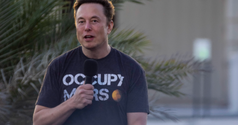 Elon Musk stands with a microphone, wearing an "occupy Mars" T-shirt