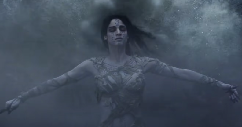 A still from The Mummy (2017) featuring the Mummy played by actress Sofia Boutella with her arms out and eyes closed while being covered in a mist