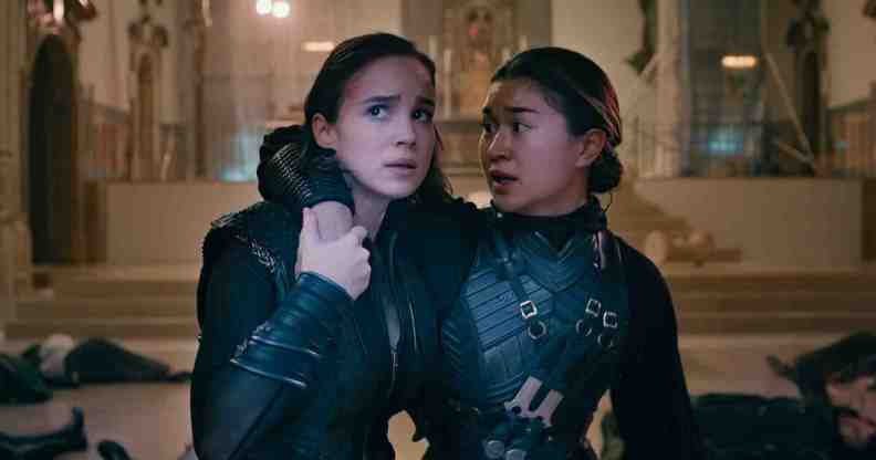 A still from Netflix series Warrior Nun showing actors Alba Baptista and Kristina Tonteri-Young as Ava and Beatrice wearing their warrior nun costumes; and Ava is supporting Beatrice in a room with bodies lying on the floor