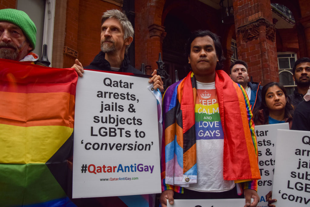 A protester holds a placard which states 'Qatar arrests, jails and subjects LGBTs to conversion' during a demonstration.