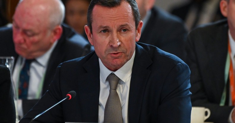Western Australia Premier Mark McGowan dressed in a dark suit, white shirt and grey tie sits in front of a microphone