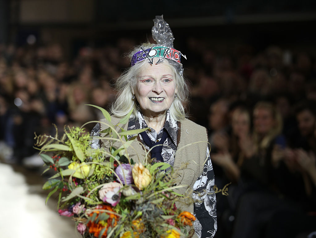 Vivienne Westwood walking a runway holding flowers