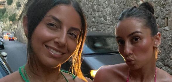 A photo shows two women, one is wearing a green bikini, and the other a pink bikini. The woman on the left is smilng while the other one is pouting