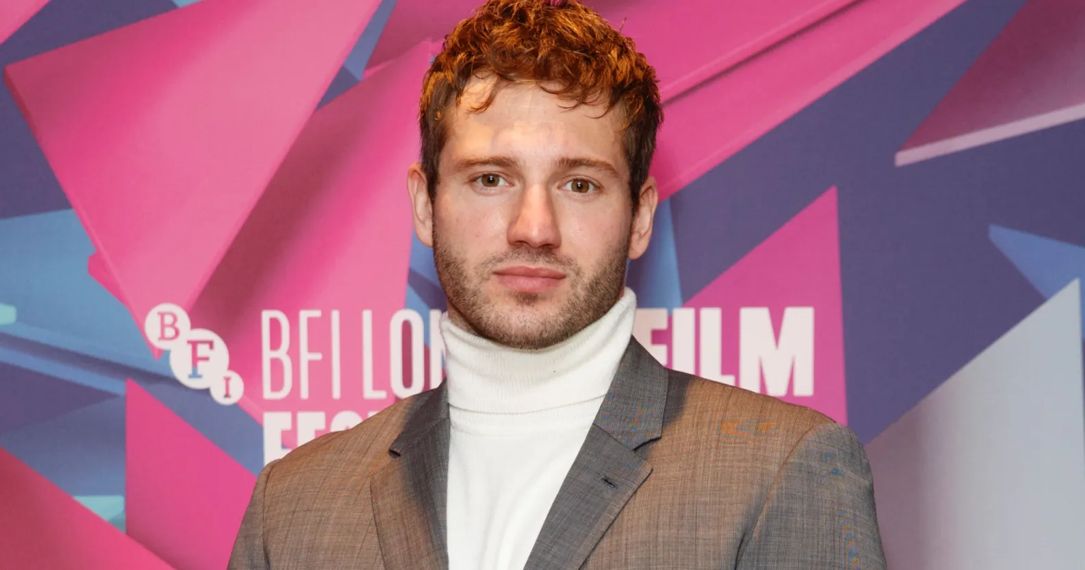 Actor Alexander Lincoln wearing a silver grey suit jacket over a white turtleneck sweater poses for the cameras at the London Film Festival. (Getty)