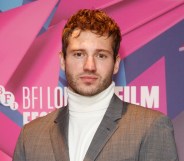 Actor Alexander Lincoln wearing a silver grey suit jacket over a white turtleneck sweater poses for the cameras at the London Film Festival. (Getty)
