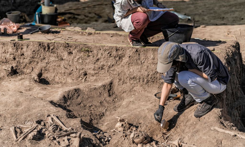 Archaeologists dust at the site of skeletal remains.