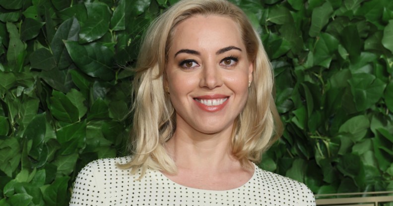 Aubrey Plaza smiling as she wears white and black dotted top.