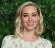 Aubrey Plaza smiling as she wears white and black dotted top.