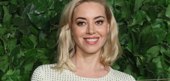 Aubrey Plaza smiling as she wears white and black dotted top.
