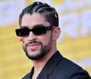 A photo shows actor Benito Antonio Martínez Ocasio aka Bad Bunny wearing a black suit jacket and sunglasses - with a short beard and smiling at a red carpet event