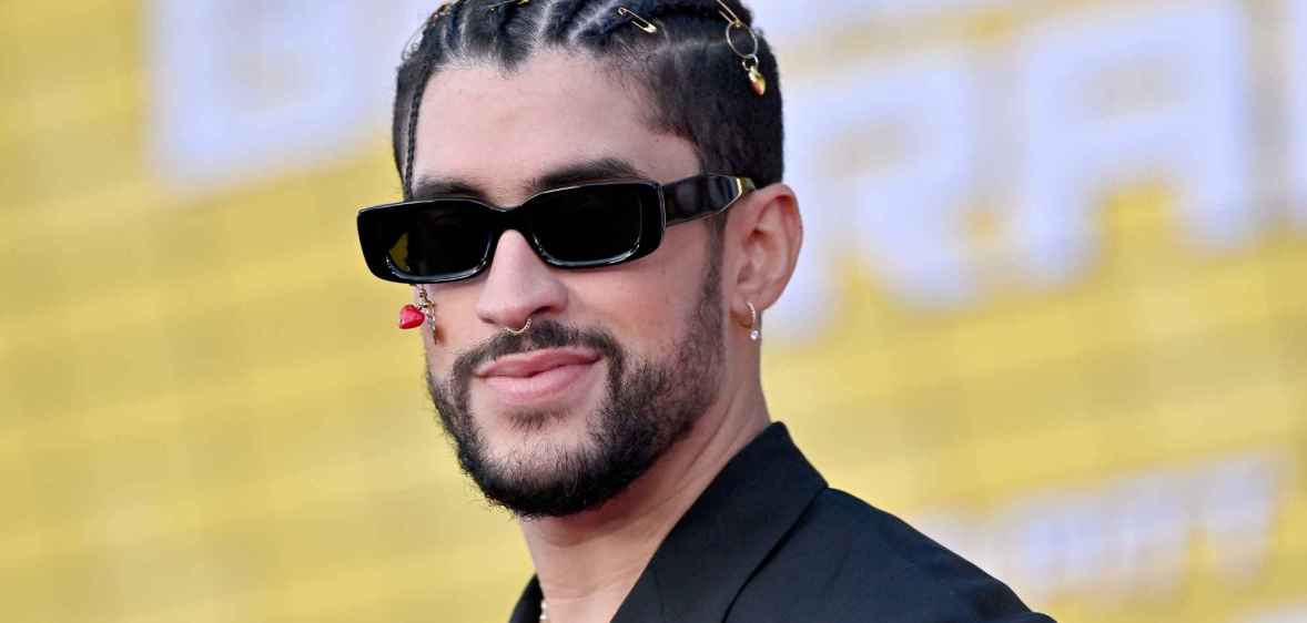 A photo shows actor Benito Antonio Martínez Ocasio aka Bad Bunny wearing a black suit jacket and sunglasses - with a short beard and smiling at a red carpet event