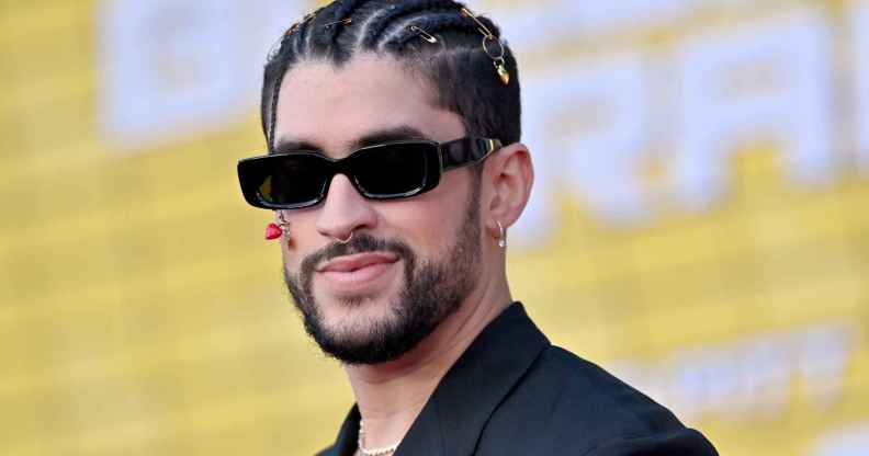 A photo shows actor Benito Antonio Martínez Ocasio aka Bad Bunny wearing a black suit jacket and sunglasses - with a short beard and smiling at a red carpet event