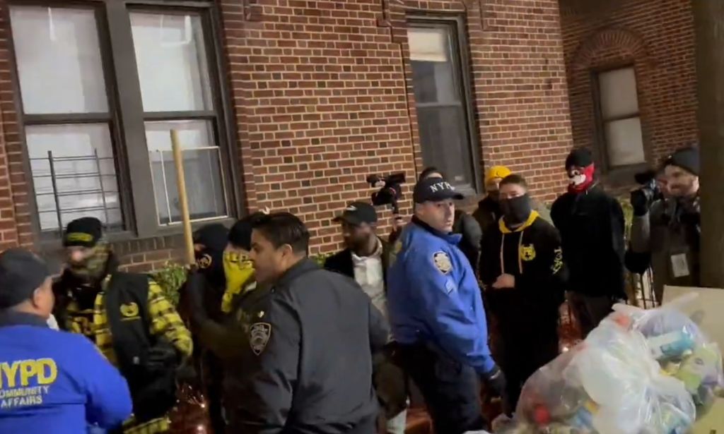 A group of Proud Boys members wearing masks are escorted by NYPD officers.