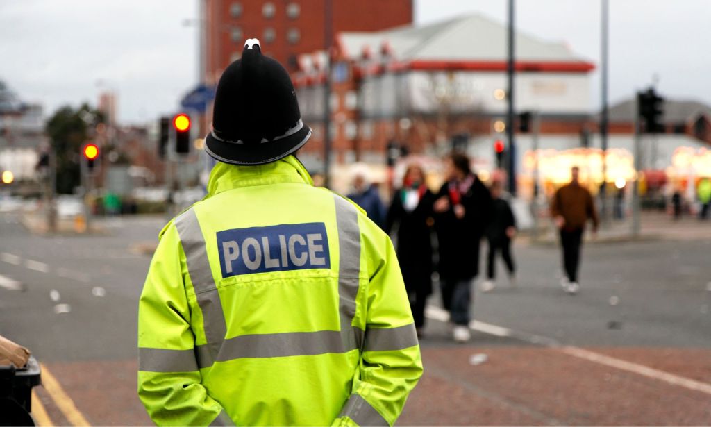 A policeman patrols in a high vis jacket around a city centre.