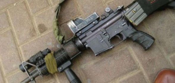 An image of an AR-15 lying down on a brick pavement.
